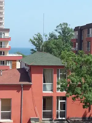 a red building with a green roof and some buildings at Maverick Hotel in Sunny Beach