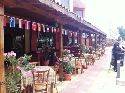 a restaurant with tables and chairs and flags on a building at Maverick Hotel in Sunny Beach