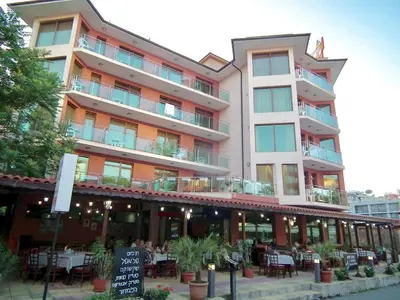 a large building with tables and chairs in front of it at Maverick Hotel in Sunny Beach