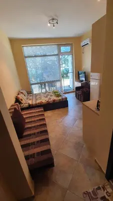 a living room with a bed and a large window at Студия първа линия Черноморец in Chernomorets
