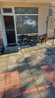 a patio with a table and benches in front of a building at Студия първа линия Черноморец in Chernomorets