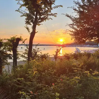 a sunset over a body of water with trees at Студия първа линия Черноморец in Chernomorets