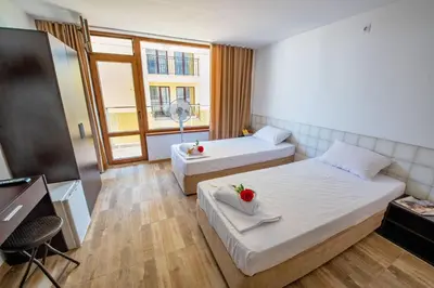 a hotel room with two beds and a window at Guest House Elidis in Primorsko
