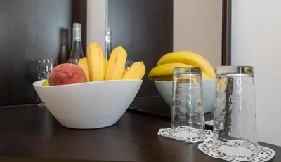 a bowl of fruit on a table with two glasses at Guest House Elidis in Primorsko