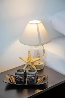 a table with a lamp and a starfish next to a bed at Guest House Elidis in Primorsko