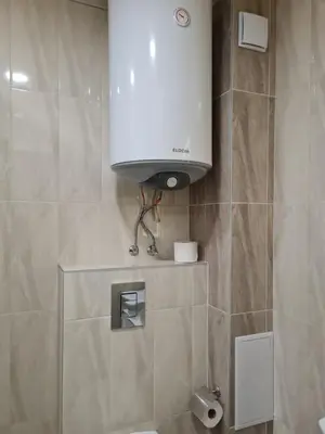 a bathroom with a toilet and a white tank at Ilarion 5 studio at Top Center in Varna City