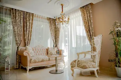 a living room with a couch and a chair and a chandelier at Menada Harmony Suites X in Burgas City