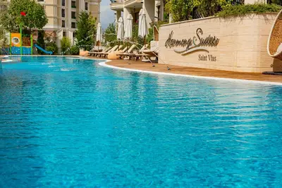 a large blue swimming pool with chairs in a building at Menada Harmony Suites X in Burgas City