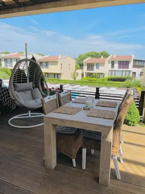 a table and chairs on a deck with a swing at Arapya Beach Apartment in Tsarevo