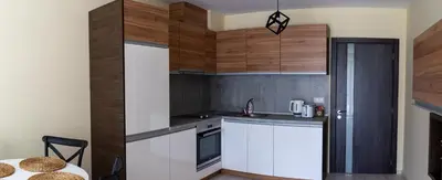 a small kitchen with wooden cabinets and a table at La Familia Apartments in Varna City