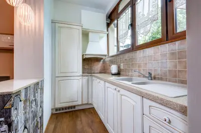 a kitchen with white cabinets and a sink and windows at Family Apartment - COMFORT IN THE CENTER in Burgas City