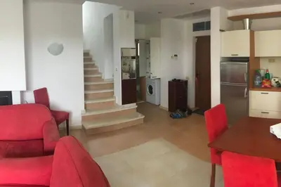 a kitchen and living room with red chairs and a table at Sun Village Villa 6 in Byala