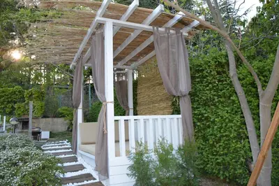 a white pergola with a white fence and curtains at Milennia Family Hotel in Sunny Beach