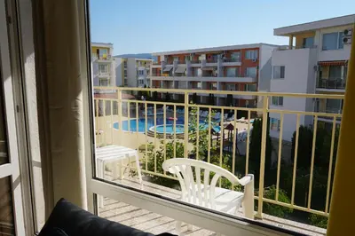 a balcony with a chair and a view of a pool at 2 Zimmer Wohnung in Sunny Beach