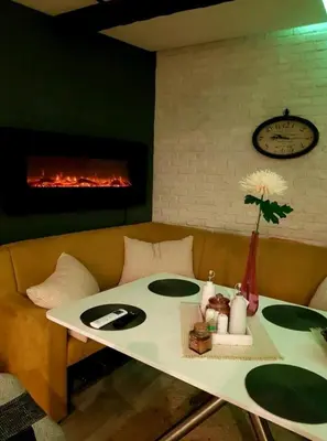 a room with a table and a couch with a fireplace at Синьо лято in Burgas City
