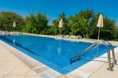 a large swimming pool with chairs and umbrellas at Menada Apolon Apartments in Sozopol