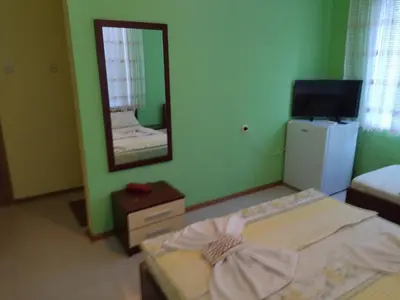 a room with a mirror and a bed and a television at Фамилна къща Джоко in Kiten