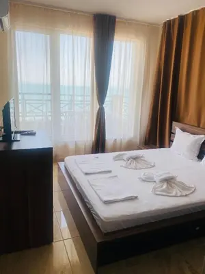 a bedroom with a bed with white sheets and a window at Golden Sea View New in Pomorie