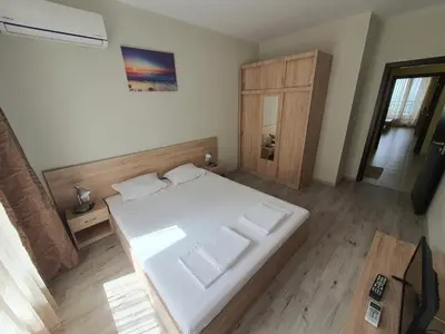 a bedroom with a white bed and a wooden floor at Таня 8 in Pomorie