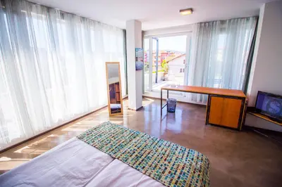 a room with a bed and a desk and windows at VIDA in Lozenets