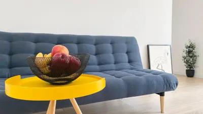 a bowl of fruit on a yellow table in front of a couch at APARTELLO Modern Apartments in DownPARK in Sunny Beach