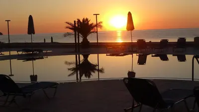 a sunset by a pool with chairs and umbrellas at Seafront Apartment im Obzor Beach Resort in Obzor