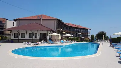 a swimming pool with chairs and umbrellas next to a building at Briz MK Apartment in Ravda