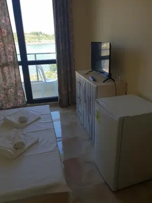 a room with a bed and a television and a window at Хотел Paradise in Tsarevo