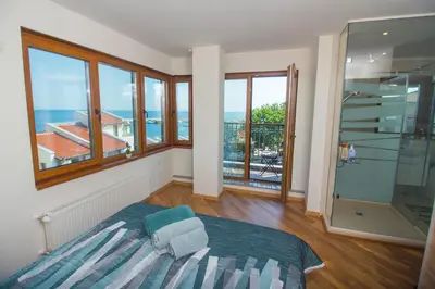 a bedroom with a bed and windows and a balcony at Breeze Guest House in Chernomorets