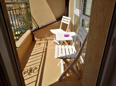 two white chairs on a balcony with a purple candle at PARUS-2-STUDIO in Pomorie