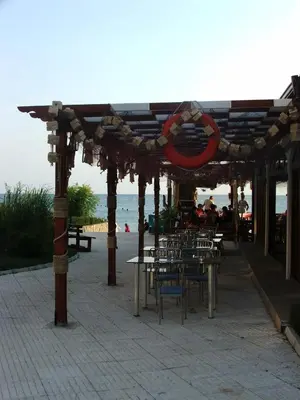 a wooden pergola with tables and chairs next to the beach at Apartamens for rent at the beach bulgaria in Sveti Vlas