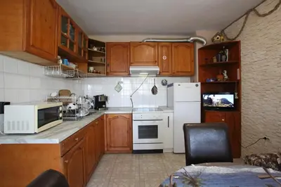a kitchen with wooden cabinets and a white refrigerator at Апартамент Вангелов in Nesebar