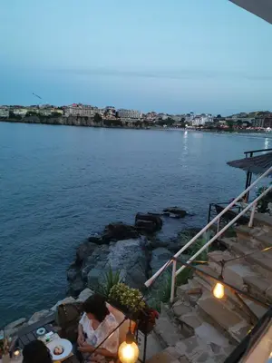 a group of people sitting at a table by the water at Hacienda Beach Apartment mit Meerblick in Sozopol