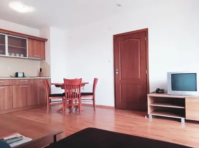 a living room with a table and a kitchen with a television at Apart Hotel Efir in Sunny Beach