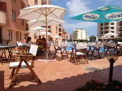 a group of tables and chairs with umbrellas at Apart Hotel Kasandra in Sunny Beach