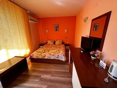 a bedroom with orange walls and a bed and a television at Guest House Kostovi in Kiten