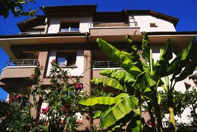 a tall white building with plants in front of it at Kastela Guest House in Chernomorets