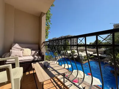 a balcony with a table and chairs and a swimming pool at Menada Apartments in Cascadas in Sunny Beach