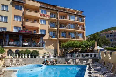 a hotel with a swimming pool in front of a building at Family Hotel Milev in Sveti Vlas