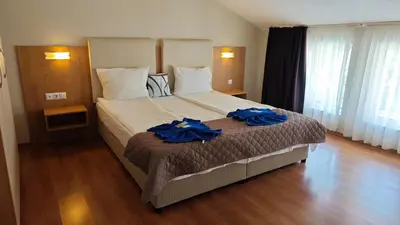 a hotel room with a large bed with blue robes on it at Family Hotel Milev in Sveti Vlas