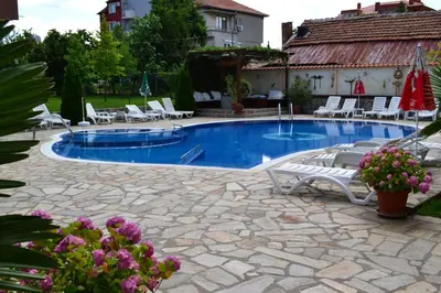a swimming pool with lounge chairs and a house at Saint George Family Hotel in Lozenets