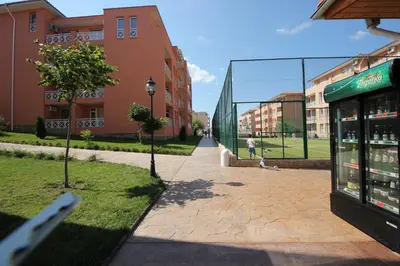 a person walking a dog on a sidewalk next to buildings at Sunny Day 6 - Menada Apartments in Sunny Beach
