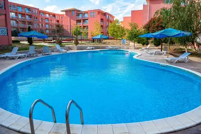 a large swimming pool with chairs and blue umbrellas at Sunny Day 6 - Menada Apartments in Sunny Beach