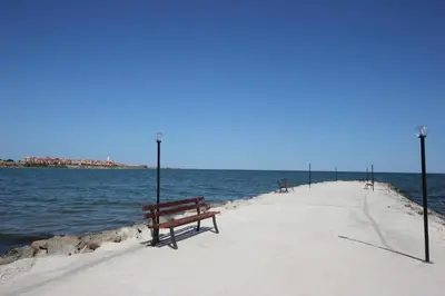 a row of benches sitting on a pier near the water at Menada Grand Resort Apartments in Aheloy