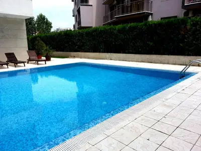 a blue swimming pool with two chairs next to a building at Eden - Menada Apartments in Sunny Beach