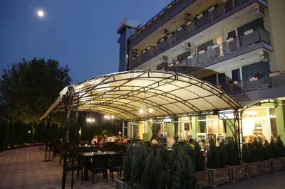 a restaurant with people sitting at tables in front of a building at Hotel Zaara in Sunny Beach