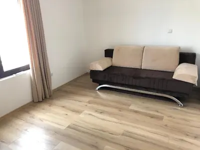 a couch in a living room with a wooden floor at Amazing apartment facing the sea in Burgas City