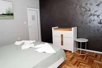 a bedroom with a bed with white sheets and a stool at Studios near to Burgas Free University in Burgas City