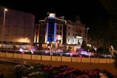 a building with a fountain in front of it at night at SEA PANORAMA appartment in Varna City