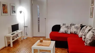 a living room with a red couch and a table at 500 steps to the sand in Varna City